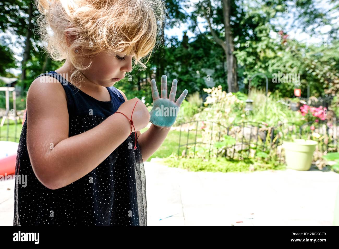 petite fille coloriant avec de la craie sur les mains à l'extérieur dans la lumière du soleil Banque D'Images