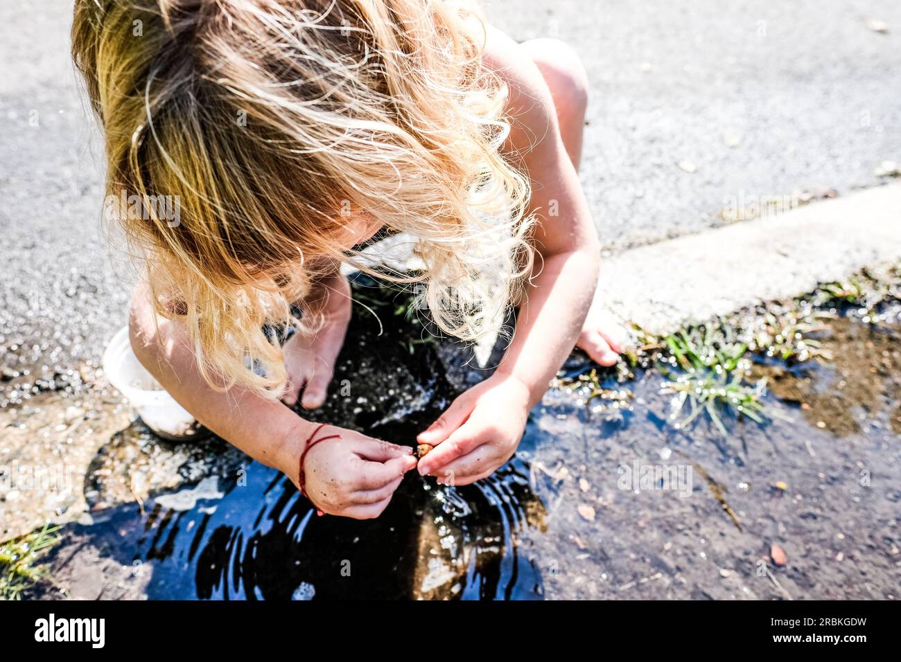 fille jouant dehors dans une flaque d'eau pieds nus dans la lumière du soleil Banque D'Images