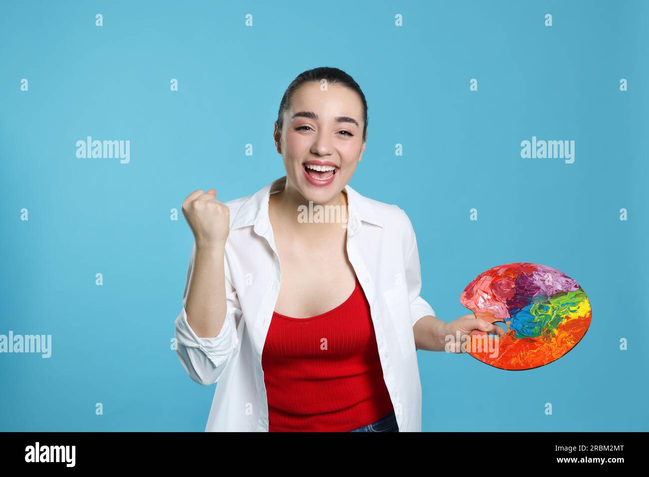 Femme avec palette de peinture sur fond bleu clair. Jeune artiste Banque D'Images