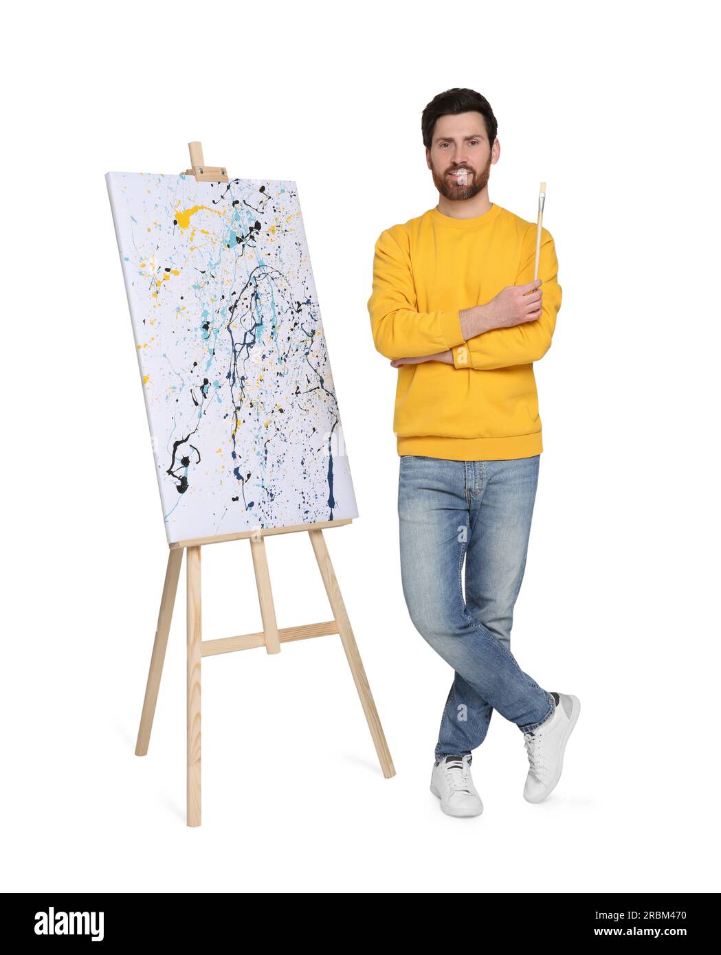 Homme heureux avec brosse près du chevalet avec peinture sur fond blanc. Passe-temps créatif Banque D'Images
