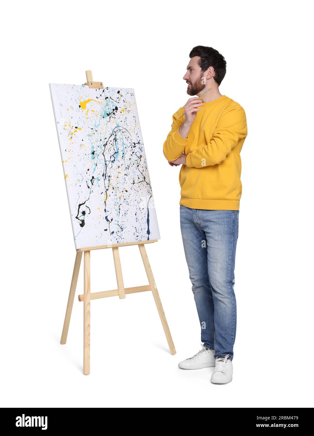 Homme avec le pinceau près du chevalet avec la peinture sur fond blanc. Passe-temps créatif Banque D'Images