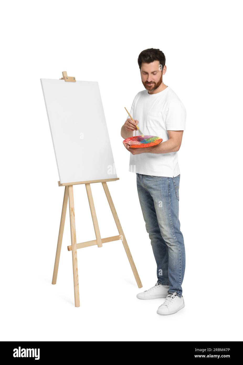 Homme avec pinceau et peinture de palette d'artiste sur fond blanc. Utiliser un chevalet pour tenir la toile Banque D'Images