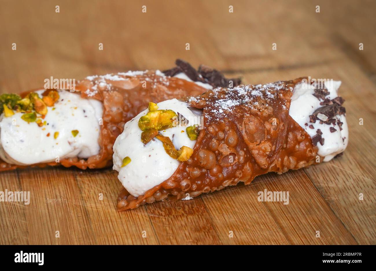 Un cannoli italien rempli de crème de ricotta sur planche de bois. Banque D'Images