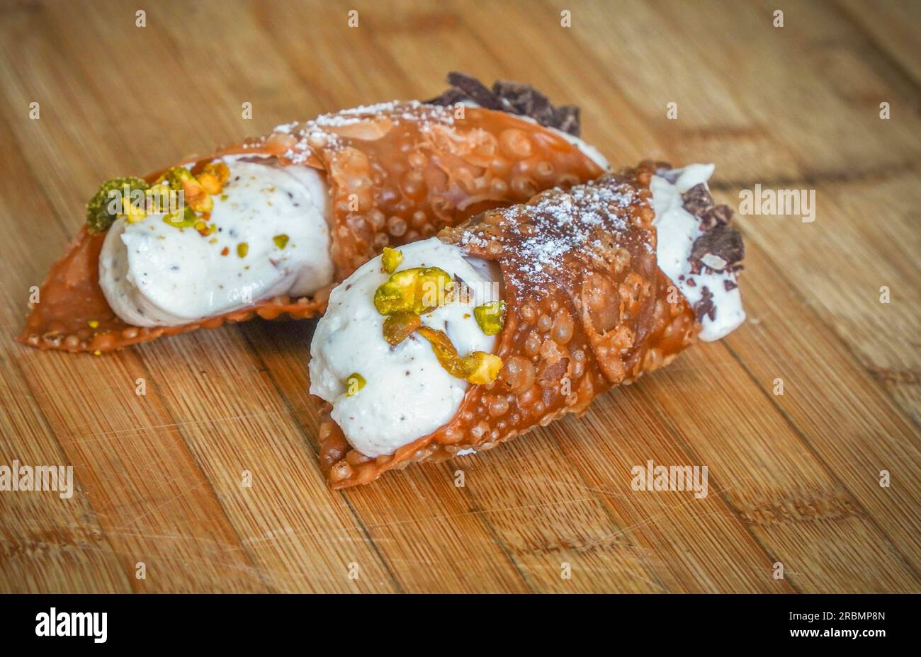 Un cannoli italien rempli de crème de ricotta sur planche de bois. Banque D'Images