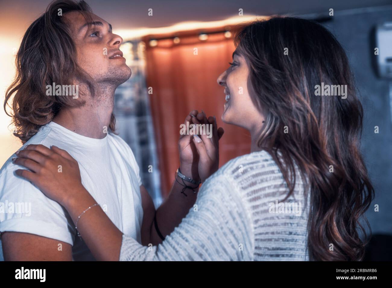 À l'intérieur de la maison couple de tournage dansant dans la salle de séjour avoir le plaisir, sourire et loughing - lumière jaune et bleue. Les amoureux ont pris des photos de danse en train de flirter en appréciant le Banque D'Images