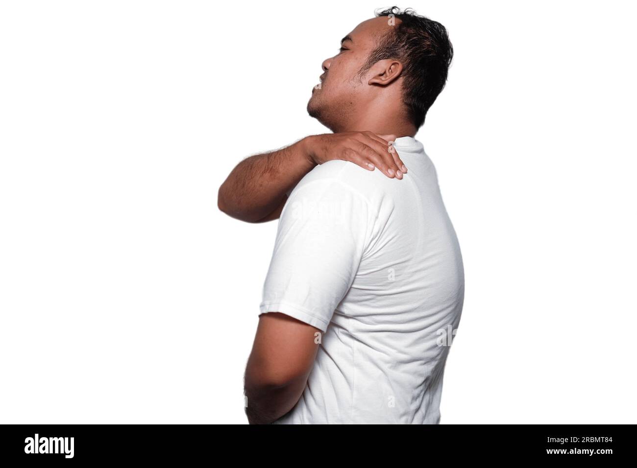 Une photo d'un asiatique mal de dos, et douleur à l'épaule portant un T-shirt blanc isolé par fond blanc. Banque D'Images