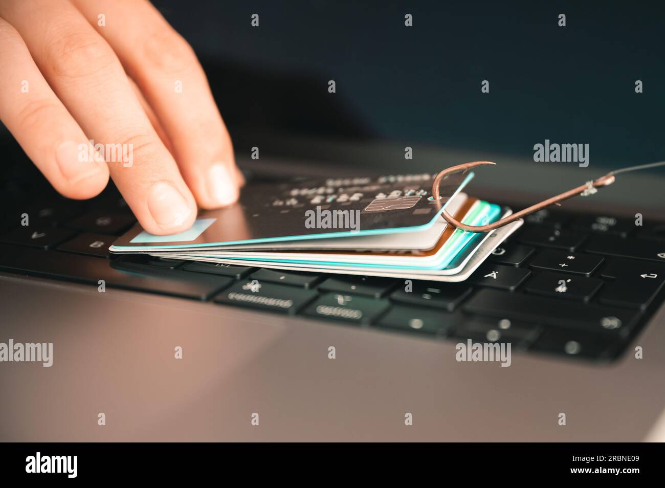 Visualisation d'une personne essayant de prévenir le phishing et la fraude en ligne en tenant une carte de crédit fuité sur un clavier de PC suspendu à un hameçon Banque D'Images