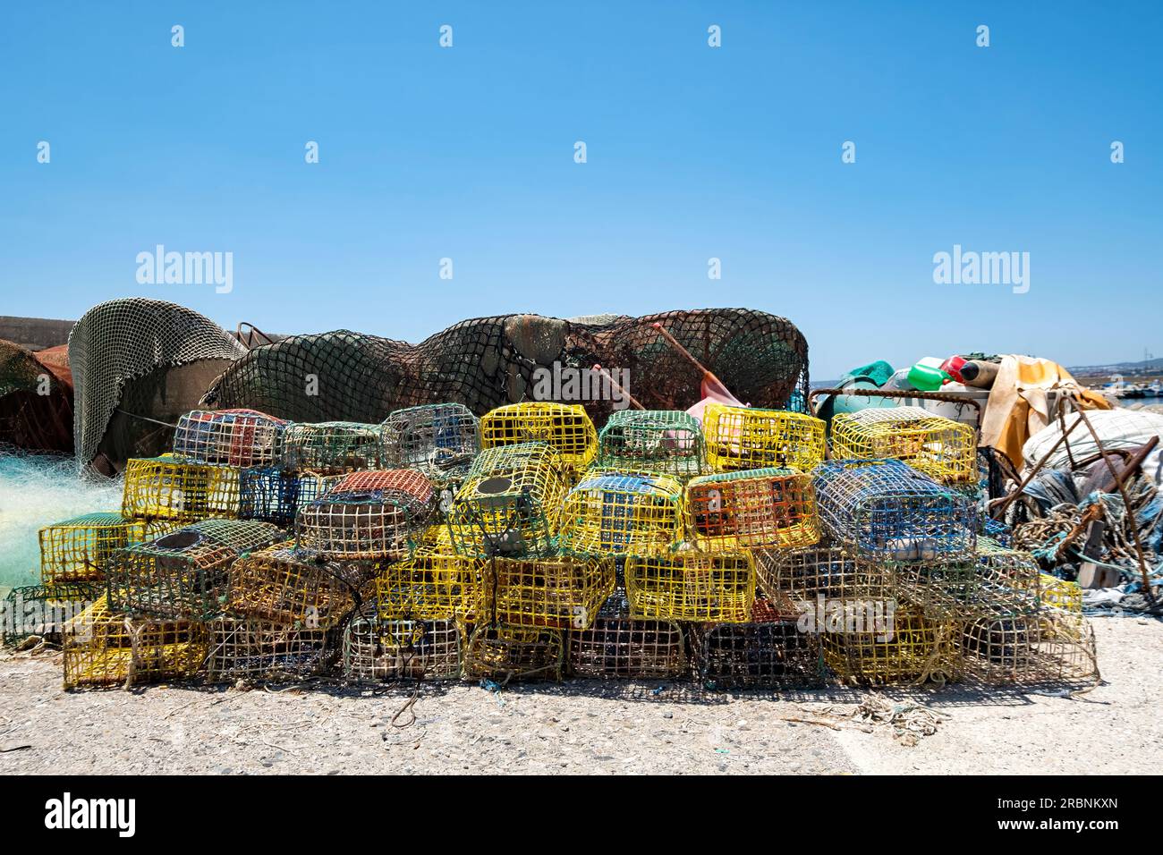 Une pile de pots ou de paniers de homard et de crabe en plastique colorés laissés à sécher par un pêcheur sur le quai du vieux port, Estepona, Espagne Banque D'Images