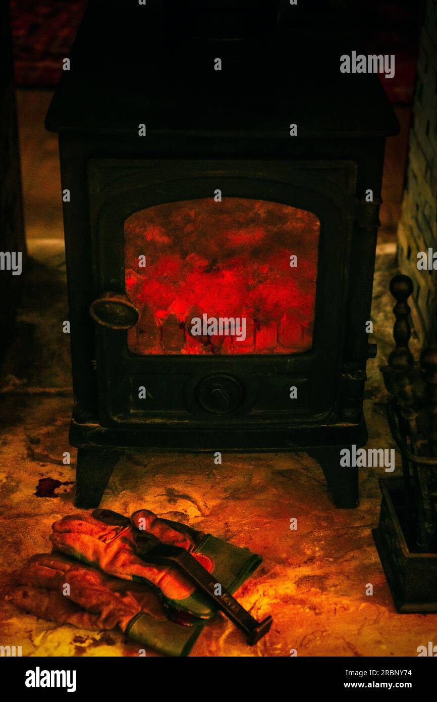 Brûleur en rondins dans la cheminée avec des gants pour les cuiseurs de fer Banque D'Images