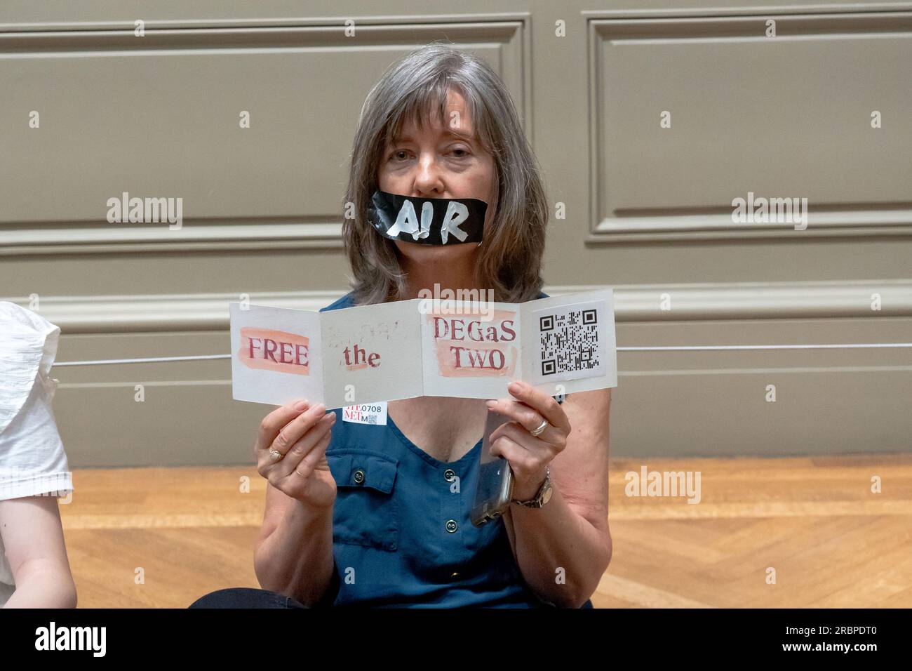 New York, États-Unis. 8 juillet 2023. Un membre de extinction Rebellion NYC et Rise and Resist avec une bande de ruban adhésif sur la bouche, sur laquelle sont écrits les mots ''Air'' tient un signe lors d'une manifestation de solidarité mise en scène. Extinction Rebellion NYC et Rise and Resist organisent une manifestation appelant à abandonner les charges contre Joanna Smith et Tim Martin devant le Metropolitan Museum of Art de New York. Joanna Smith et Tim Martin ont étalé de la peinture sur le cas d'une sculpture de Degas lors d'un acte de désobéissance civile à la National Gallery of Art de Washington, DC. (Image de crédit : © Ron Adar/SOPA Images via Z Banque D'Images