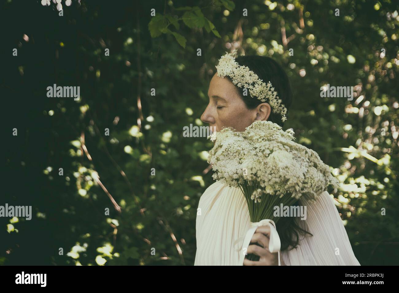 Femme en blouse blanche avec bouquet de fleurs et bandeau II Banque D'Images
