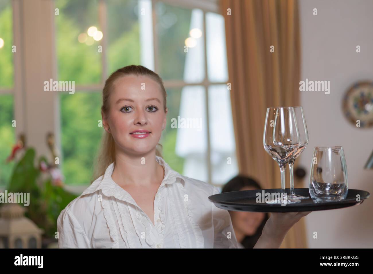 Jeune blonde serveuse dans restaurant holding a tray plein de verres Banque D'Images