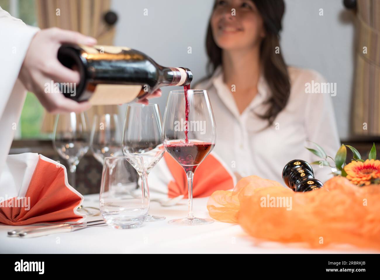 Waiter serving vin rouge dans un restaurant gastronomique avec happy female customer sitting at table Banque D'Images