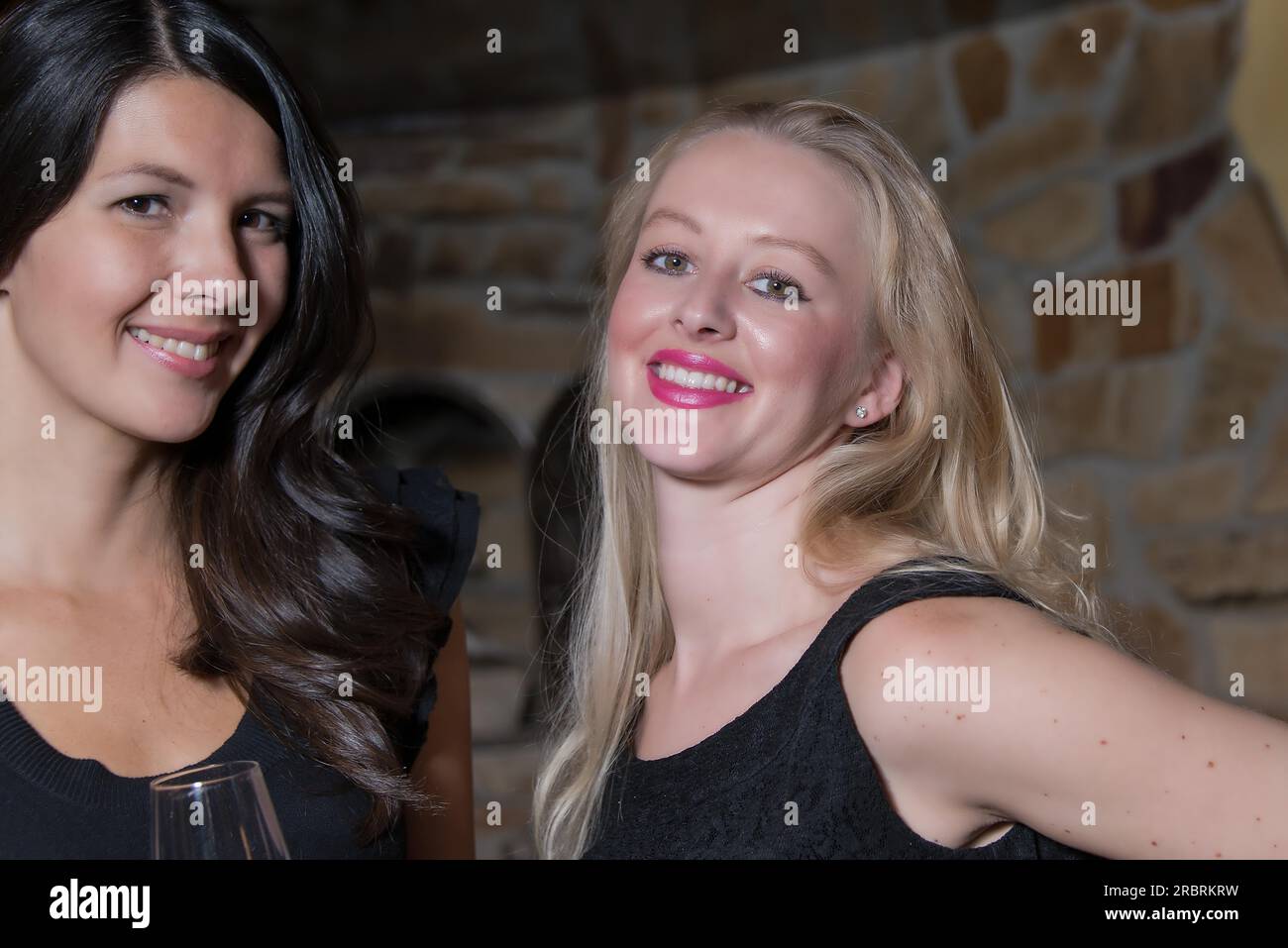 Deux jeunes femmes élégantes et sophistiquées en tenue de soirée noire élégante célébrant ensemble Banque D'Images