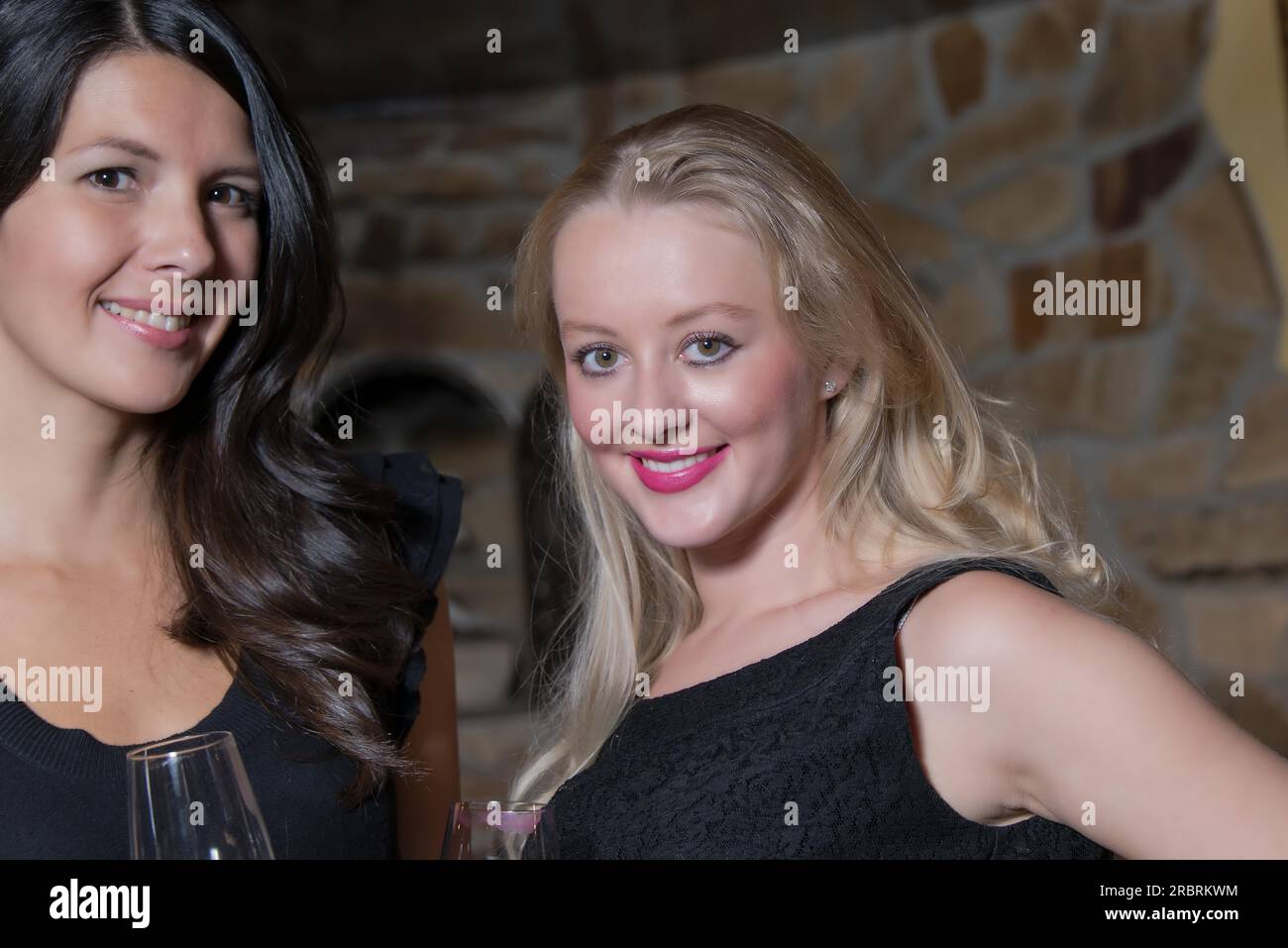 Deux jeunes femmes élégantes et sophistiquées en tenue de soirée noire élégante célébrant ensemble Banque D'Images