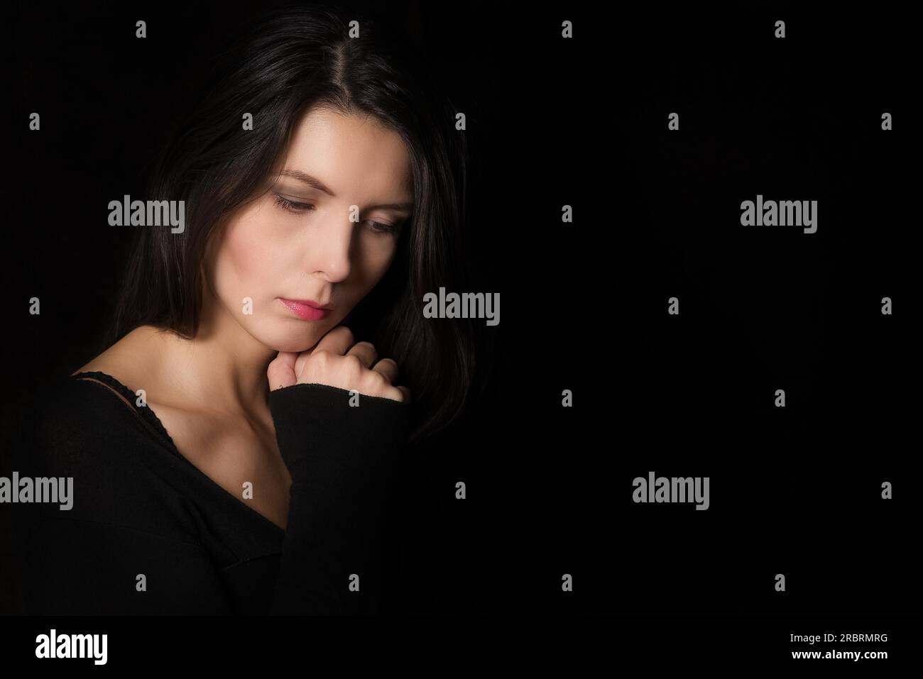 L'atmosphère sombre portrait d'une belle femme sereine introspective avec les yeux baissés et une expression pensive dans une rêverie profonde Banque D'Images