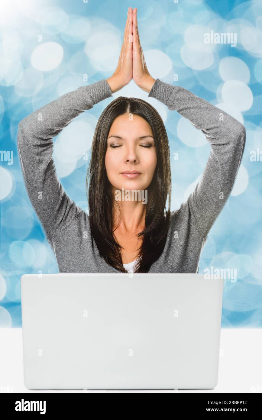 Pretty long Hair Jeune femme méditant avec les mains sur la tête et les yeux fermés devant un ordinateur portable, capturée en Studio sur Abstract Blue Banque D'Images
