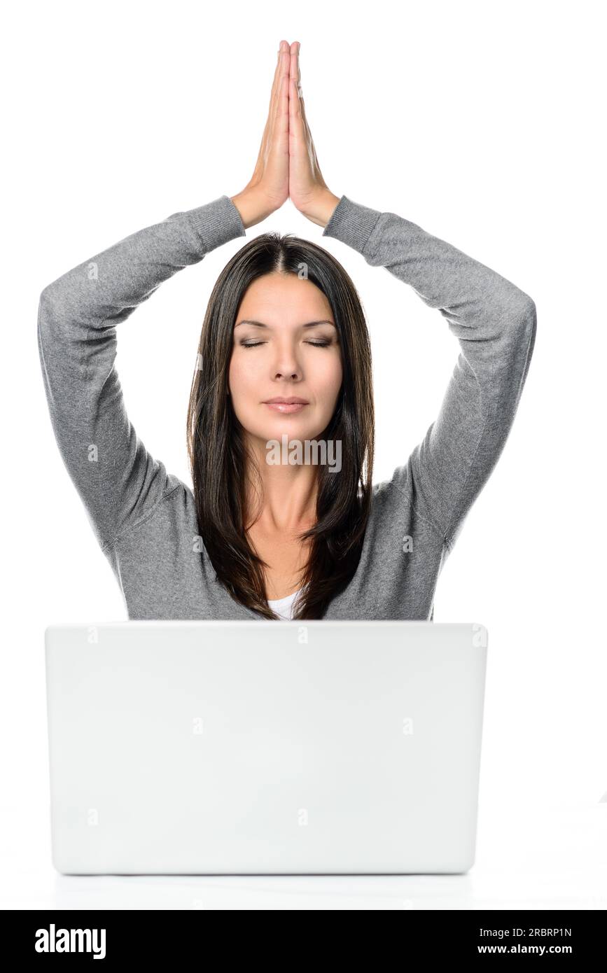 Jolie Jeune femme Cheveux Longs méditant avec les mains sur la tête et ferma les yeux en face d'un ordinateur portable, isolé sur fond blanc Banque D'Images