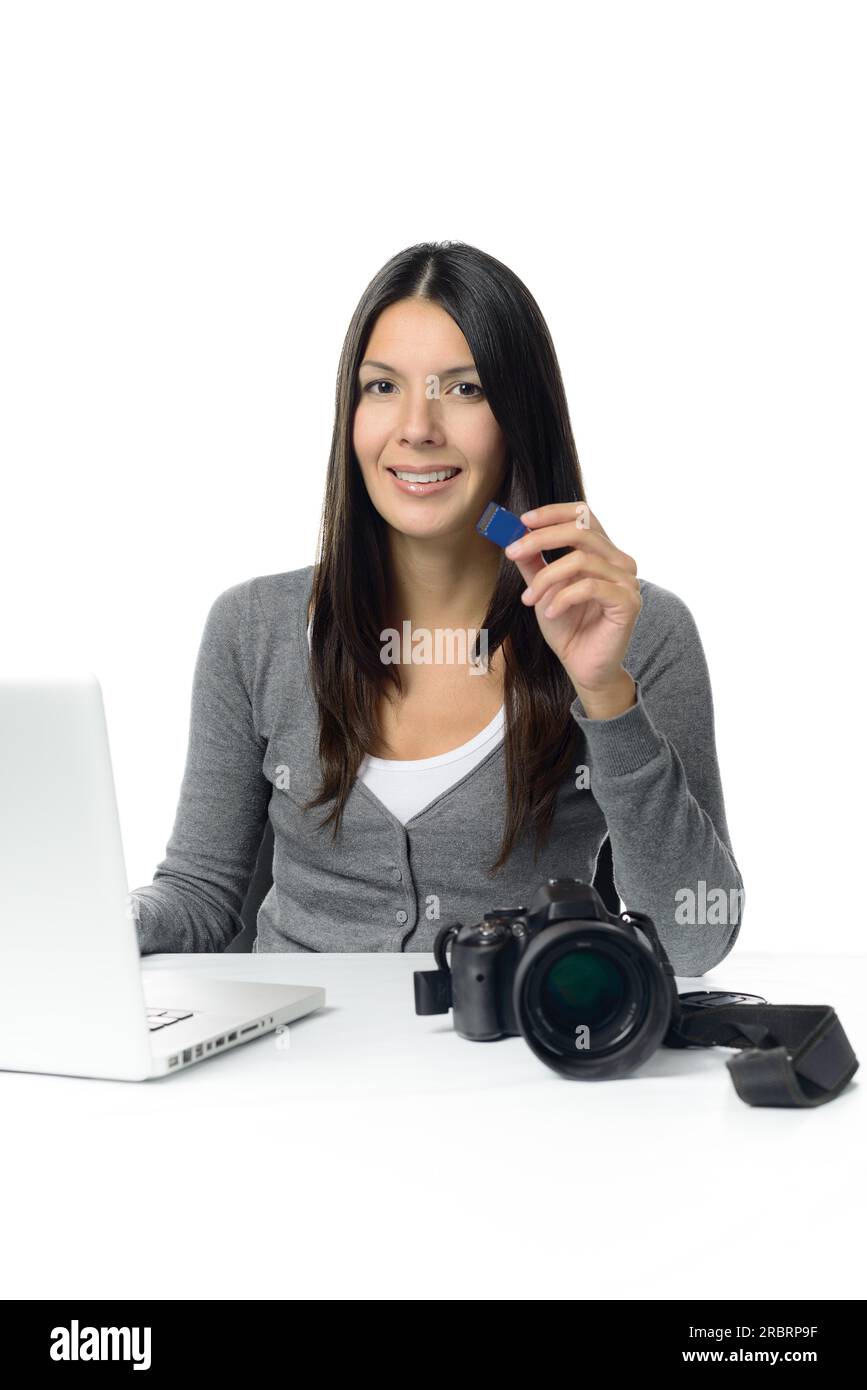 Photographe féminine attrayante montrant sa carte sd avec ses nouvelles photos prêtes à être copiées sur son ordinateur portable pour le montage, isolé sur blanc Banque D'Images