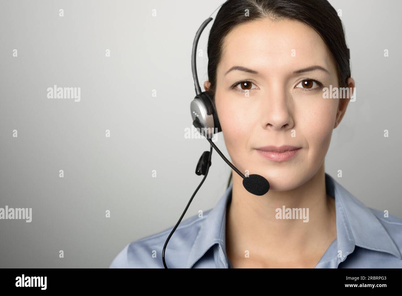 Opérateur féminin attrayant de centre d'appels, assistant de service client ou télévendeur portant un casque regardant la caméra avec un charmant amical Banque D'Images