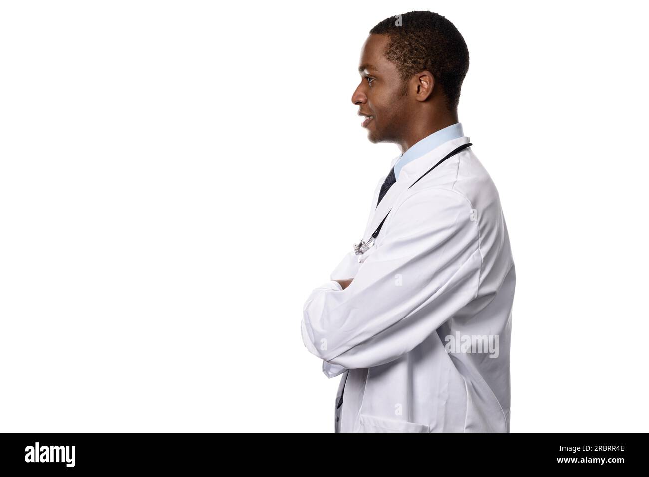 Half Body Shot d'un médecin africain en vue de côté, face à la gauche du cadre avec les bras fermés, mettant l'accent sur l'espace de copie, isolé sur blanc Banque D'Images