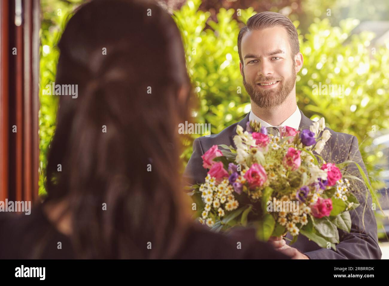 Beau Bearded Guy donnant un bouquet de fleurs fraîches à sa petite amie avec Happy facial expression Banque D'Images