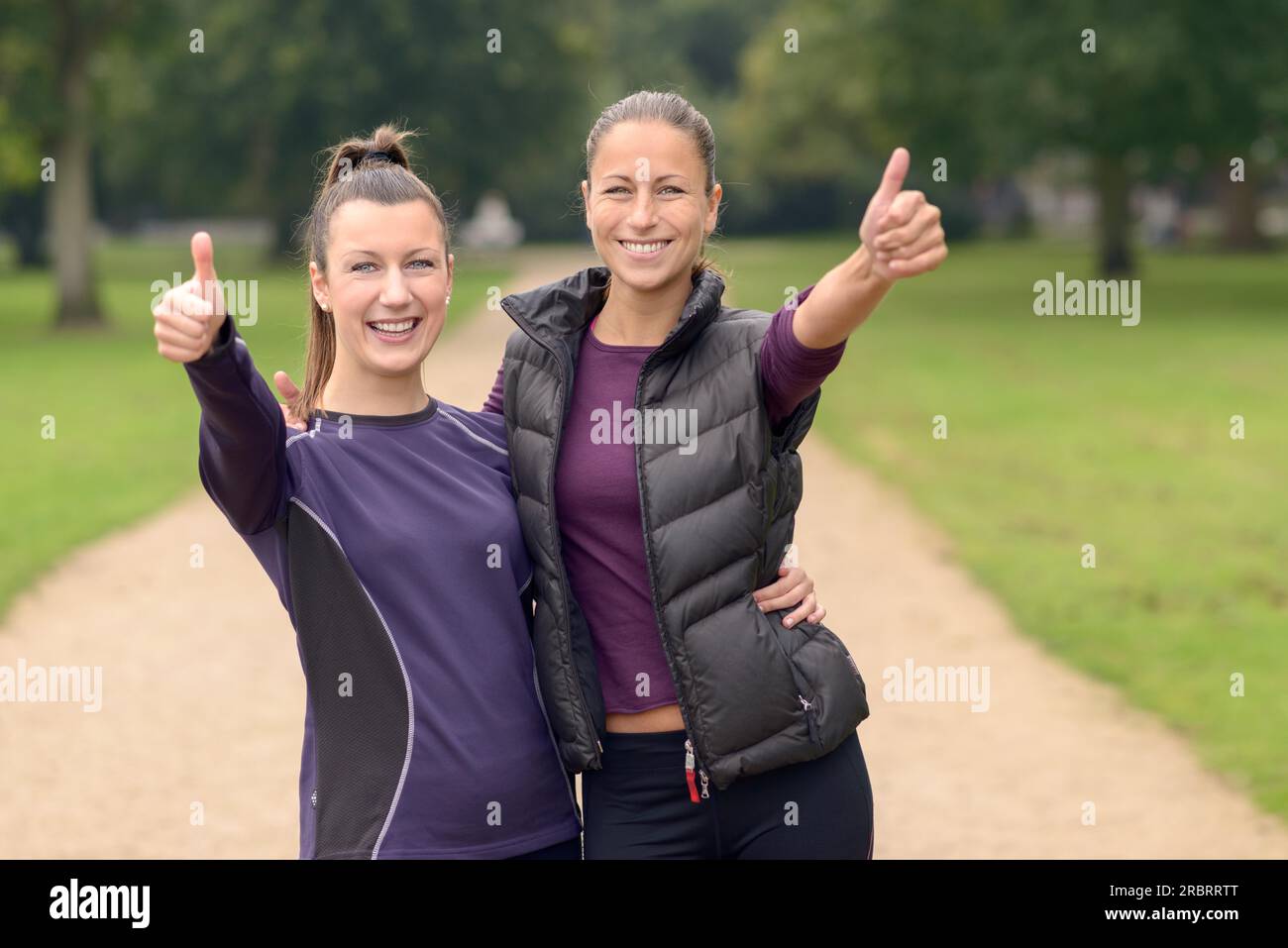 Half Body Shot de deux femmes heureuses en bonne santé au parc montrant des pouces vers le haut à la caméra après leur entraînement Banque D'Images