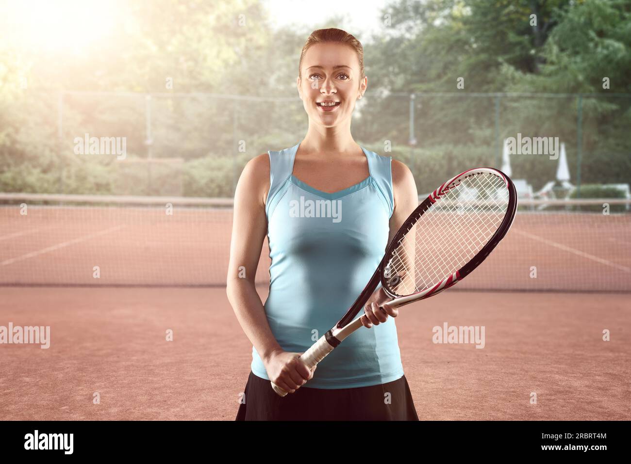 Trois quarts Portrait of smiling Athletic Blonde Woman Holding tennis racket en position d'attente sur un court de tennis Banque D'Images