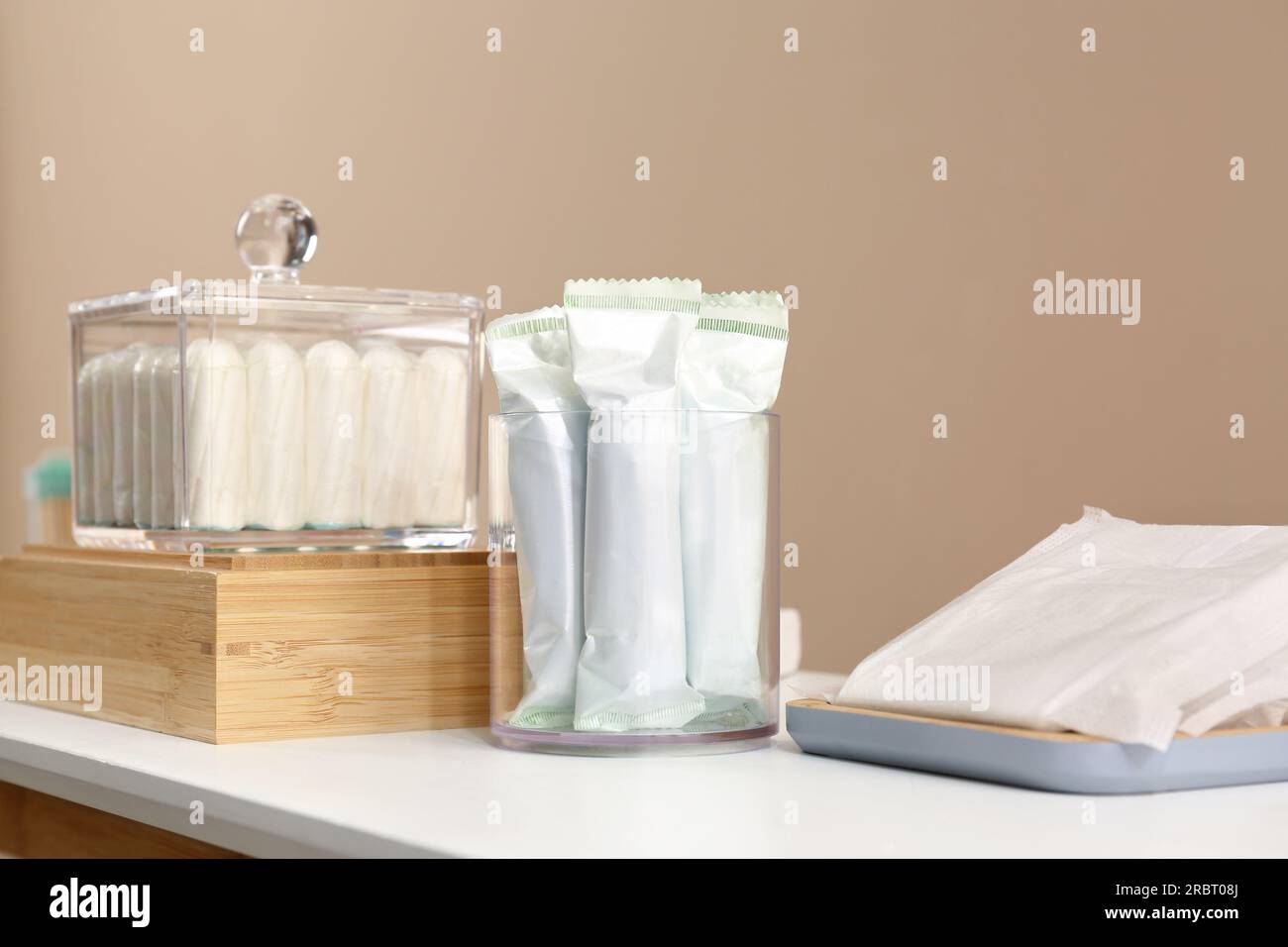 Beaucoup de tampons différents sur la table blanche près du mur beige. Produit hygiénique menstruel Banque D'Images