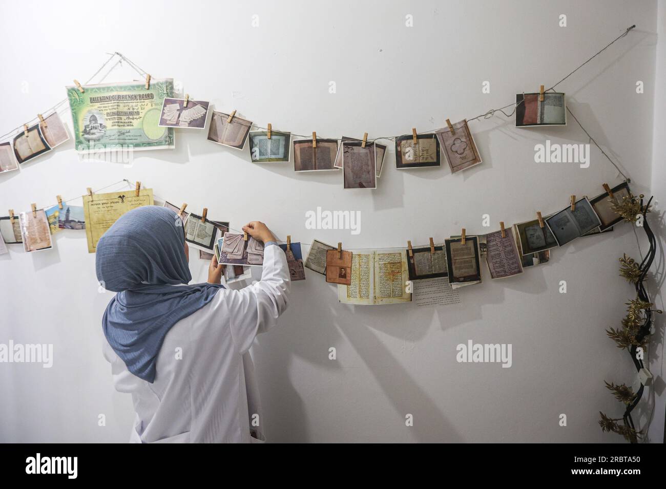 Gaza, Palestine. 10 juillet 2023. Une femme palestinienne attache des photos à la corde alors qu'elle restaure et numérise des manuscrits et des livres rares dans le laboratoire de la Fondation 'Eyes on Heritage' pour les études, la recherche et l'édition dans la ville de Gaza. Les palestiniennes travaillent à l'archivage et à la restauration de manuscrits et de livres historiques rares anciens dans un laboratoire financé par la British Library de Londres et le Hill Museum. (Photo Ahmed Zakot/SOPA Images/Sipa USA) crédit : SIPA USA/Alamy Live News Banque D'Images