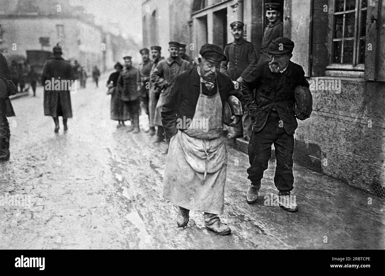 France : c. 1916 deux Français âgés partent avec leurs miches de pain qu'ils ont dû demander aux forces allemandes d'occupation. Banque D'Images