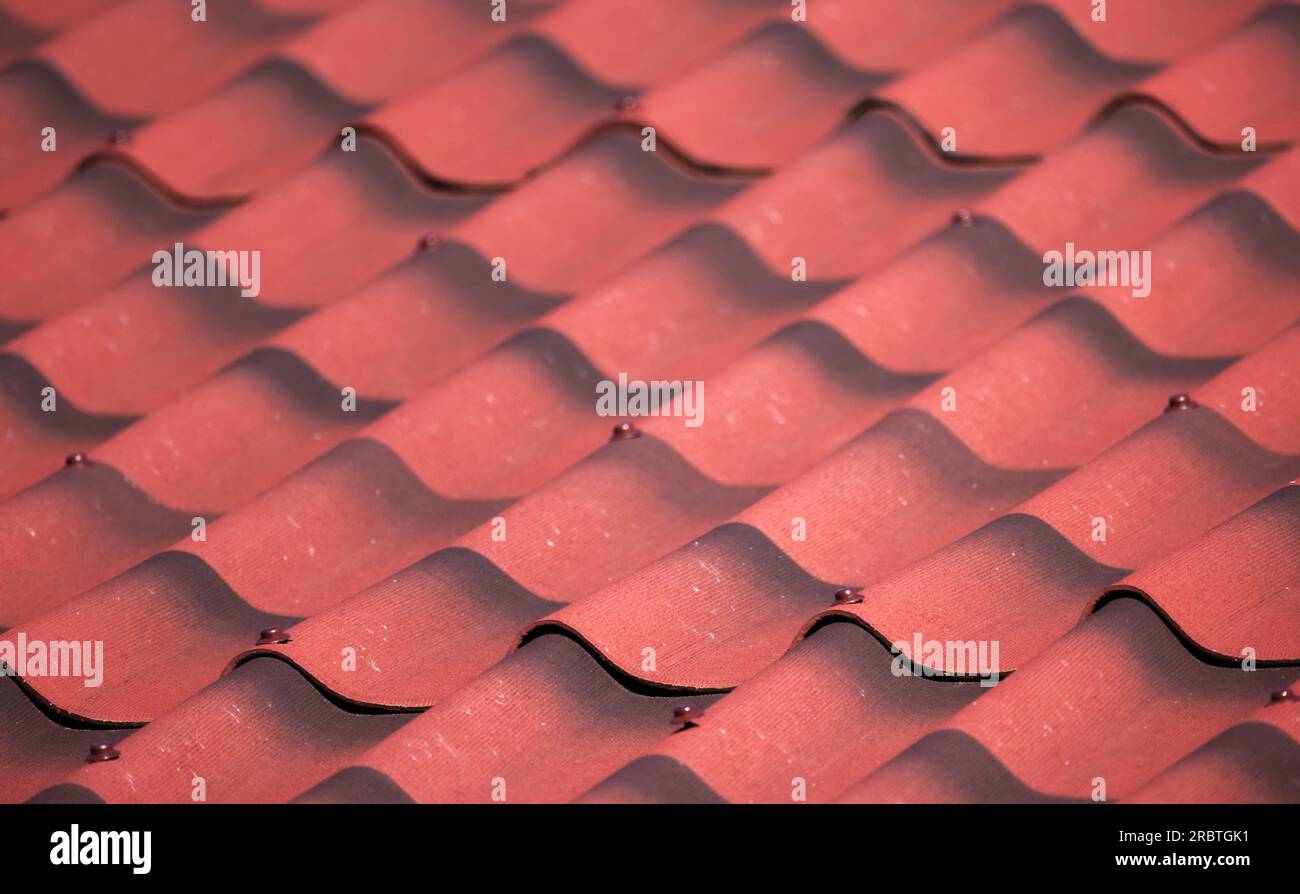 Imitation de carrelage de toit rouge en feuilles ondulées d'ardoise, fond photo rapproché du toit de maison de campagne moderne Banque D'Images