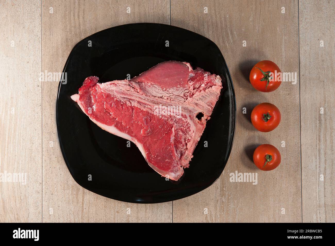 Bistecca di manzo (T - OS - Steak). Avant la cuisson et la tomate Banque D'Images