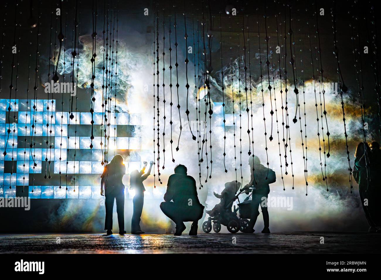 Les familles apprécient les images et les sons de la nouvelle exposition Sola, composée d'un mur de lentilles fresnel et de LED ultra-lumineuses qui simule le soleil lointain mais tout-puissant, à Beyond submergence, une installation artistique immersive de 20 000 pieds carrés organisée par le collectif d'art Squidsoup, au Propyard à Bristol. Date de la photo : mardi 11 juillet 2023. Banque D'Images