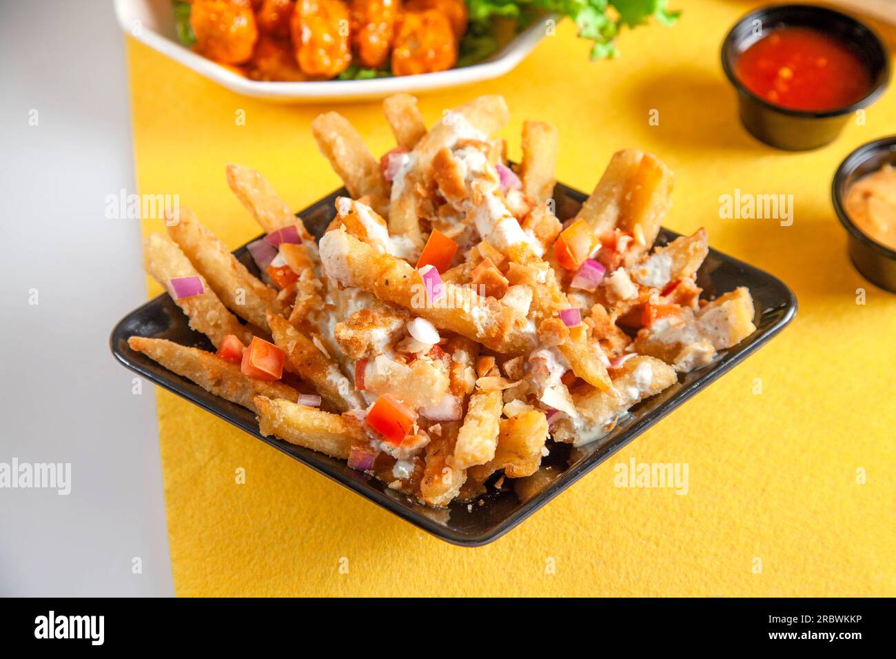 Frites de pommes de terre de chaat acidulées mélangées à l'oignon et aux tomates garnies d'une vinaigrette au yourte. Banque D'Images