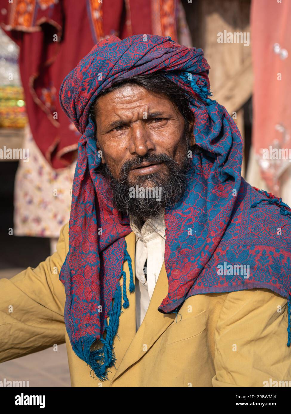 UCH Sharif, Punjab, Pakistan - 11 12 2019 : Portrait vertical d'un homme d'âge moyen du punjabi rural portant un foulard traditionnel rouge et bleu Banque D'Images