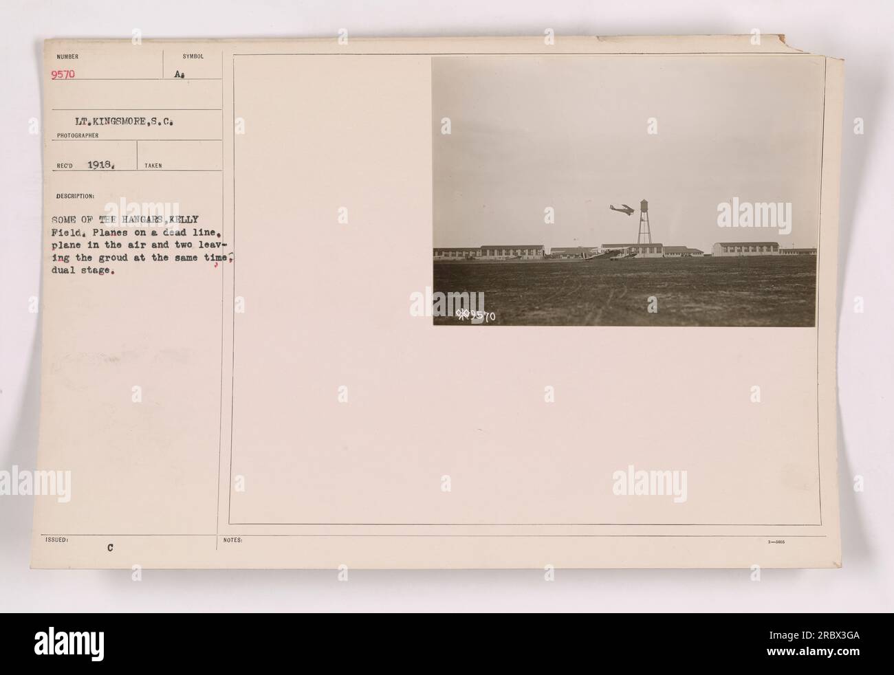 Des avions alignés sur le tarmac à Kelly Field avec des hangars en arrière-plan. Un avion est actuellement dans les airs tandis que deux autres se préparent à décoller simultanément, présentant un décollage en deux étapes. Cette photographie a été prise par le lieutenant Kingsmore en 1918 et porte le numéro 9570. Banque D'Images