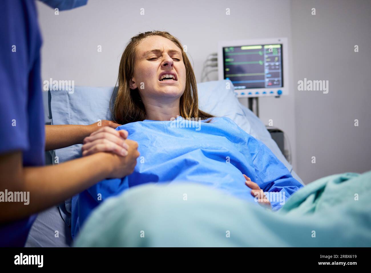 Femme enceinte, clinique et travail avec poussée, tenant les mains ou le soutien dans le lit, bébé et douleur. Mère forte, processus d'accouchement et aide à la main Banque D'Images
