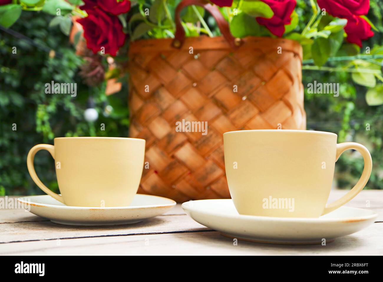 Paire de tasses à café avec des roses de panier floues en toile de fond Banque D'Images