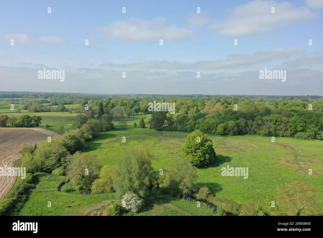 Perspective drone au-dessus des champs verts de Hook, Hampshire, Angleterre. Les images montrent un ciel clair et des champs verts se rencontrant à la ligne d'horizon. Banque D'Images