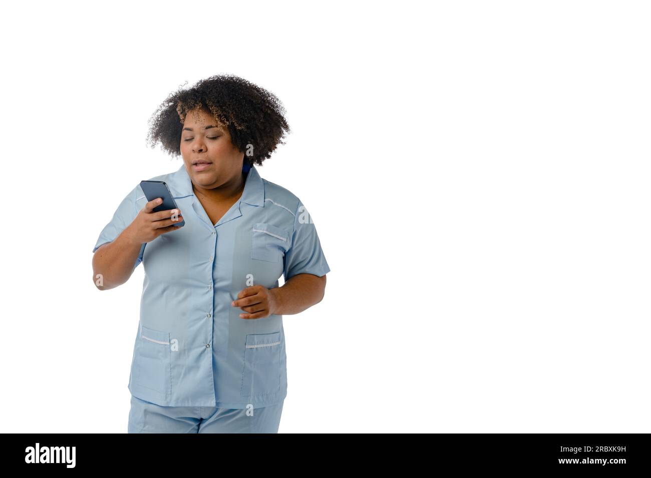 Jeune femme médicale afro-latino d'origine vénézuélienne, debout lisant un message sur son téléphone portable, fond blanc - espace copie, communication Banque D'Images