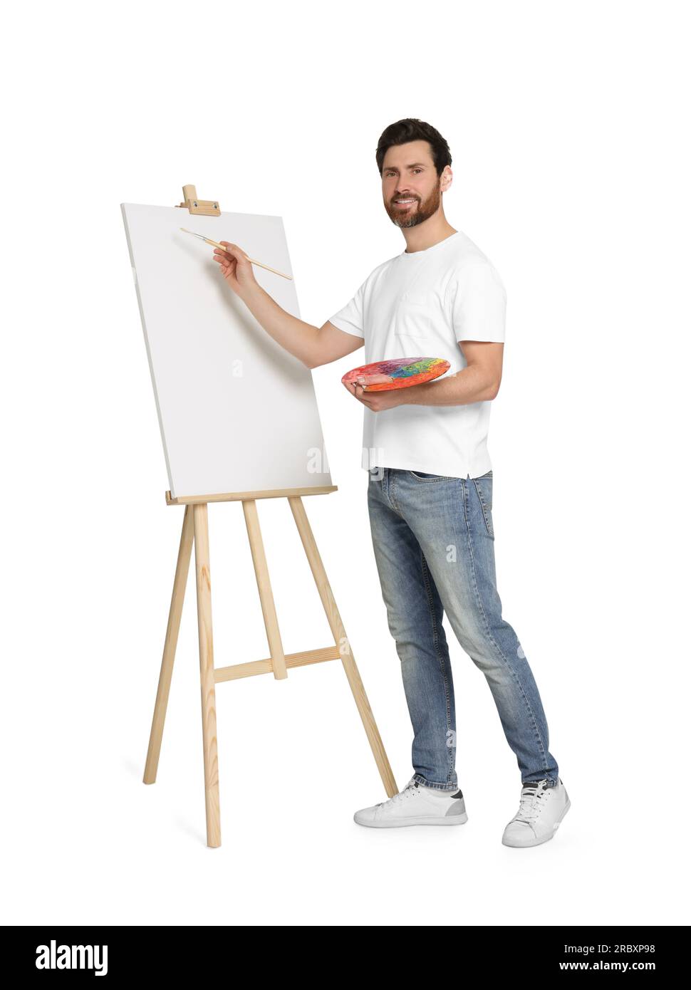 Homme avec peinture au pinceau sur fond blanc. Utilisation du chevalet pour tenir la toile Banque D'Images