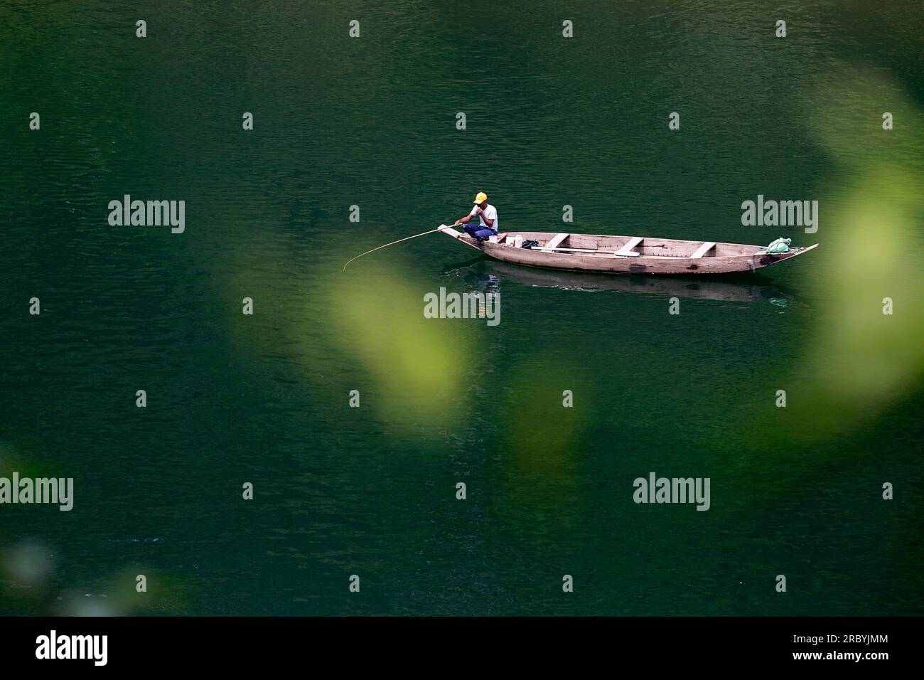 Pêcheur local sur des bateaux traditionnels en bois pêchant dans la rivière Umngot ou Dawki à Meghalaya, en Inde Banque D'Images