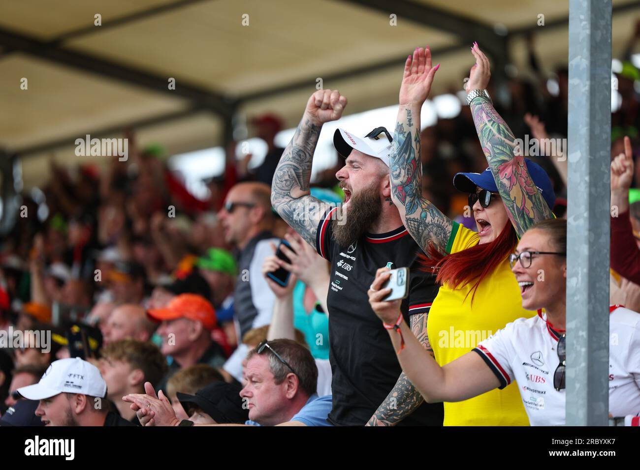 Un homme et une femme frappent l'air alors que Lewis Hamilton (GBR) de l'écurie Mercedes-AMG Petronas F1 Team dépasse un pilote et d'autres stands de supporters du Grand prix de Formule 1 Banque D'Images
