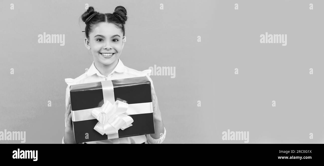joyeux enfant de l'école avec boîte cadeau sur fond bleu, anniversaire. Petite fille avec cadeau, affiche horizontale. En-tête de bannière avec espace de copie. Banque D'Images