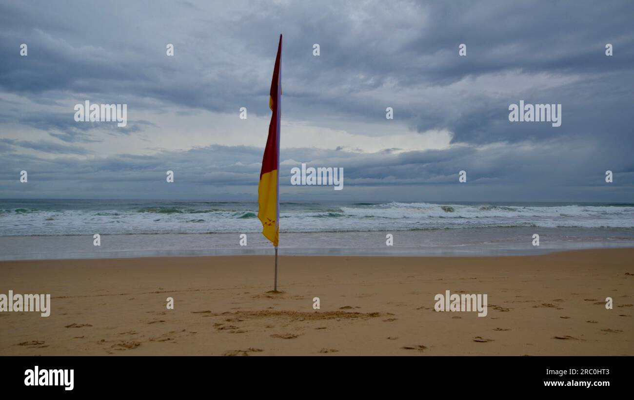 Drapeau unique de sauvetage de surf sur une plage de sable vide lors d'une journée orageuse à Sunshine Beach, Queensland Banque D'Images