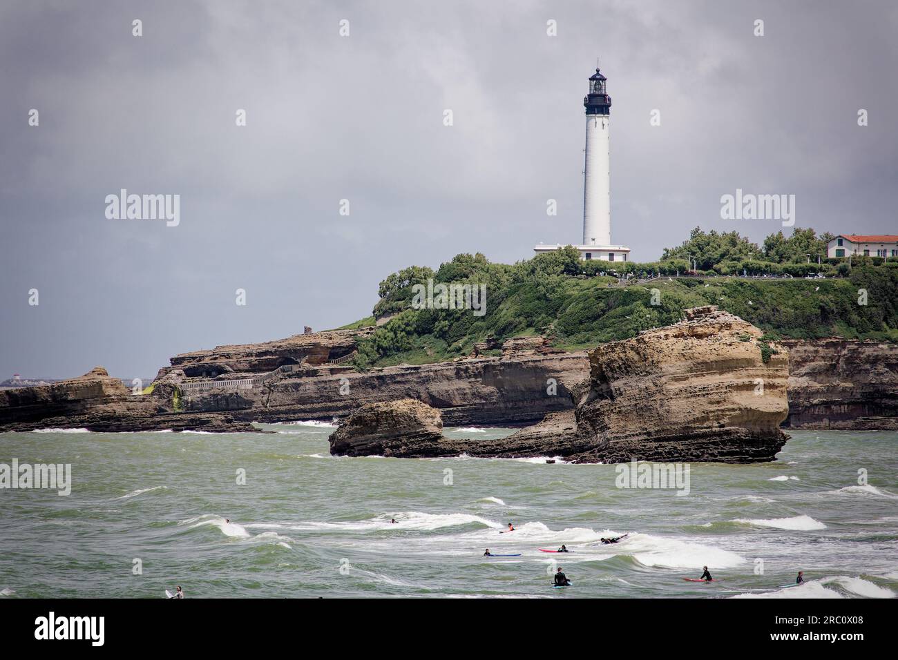 Personnes surfant devant le phare de Biarritz, France. Banque D'Images