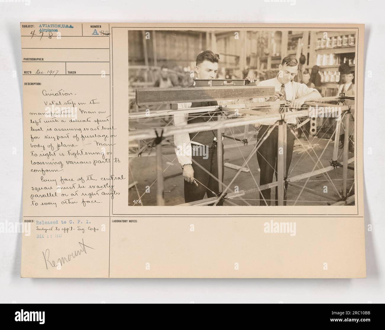 Ouvrier d'usine d'aviation utilisant un niveau à bulle délicat pour assurer le nivellement précis d'une partie clé du fuselage ou du corps principal d'un avion. Un autre travailleur serre ou desserre diverses pièces pour assurer la conformité. Toutes les faces du carré central doivent être parallèles ou à angle droit l'une par rapport à l'autre. Banque D'Images