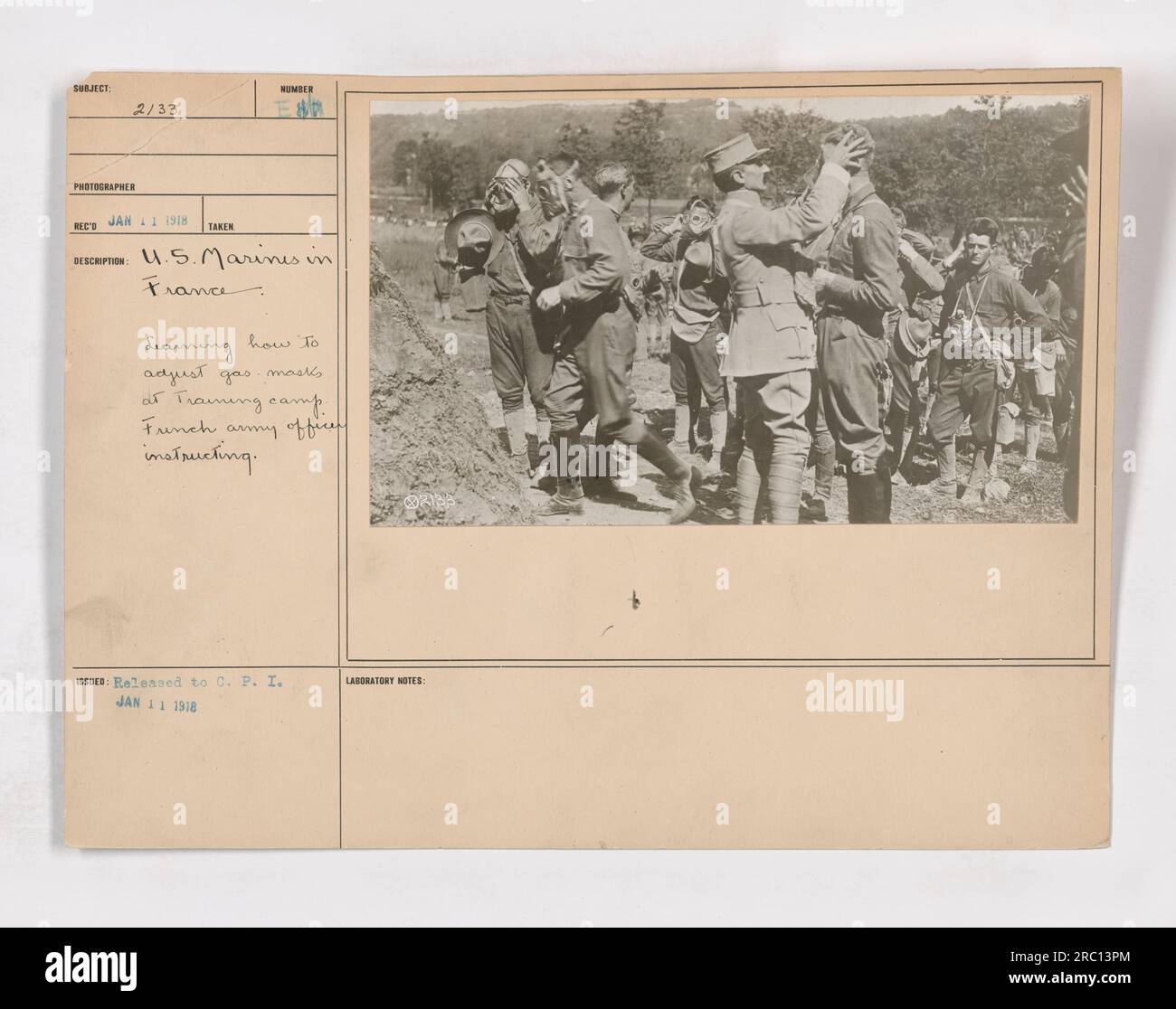 Titre : Marines des États-Unis en France, apprentissage des ajustements de masque à gaz pendant l'entraînement Légende : en janvier 1918, États-Unis Les Marines stationnés en France ont suivi une formation cruciale sur la façon d'ajuster correctement leurs masques à gaz. Cette image capture un officier de l'armée française instruisant les marines dans un camp d'entraînement. Banque D'Images