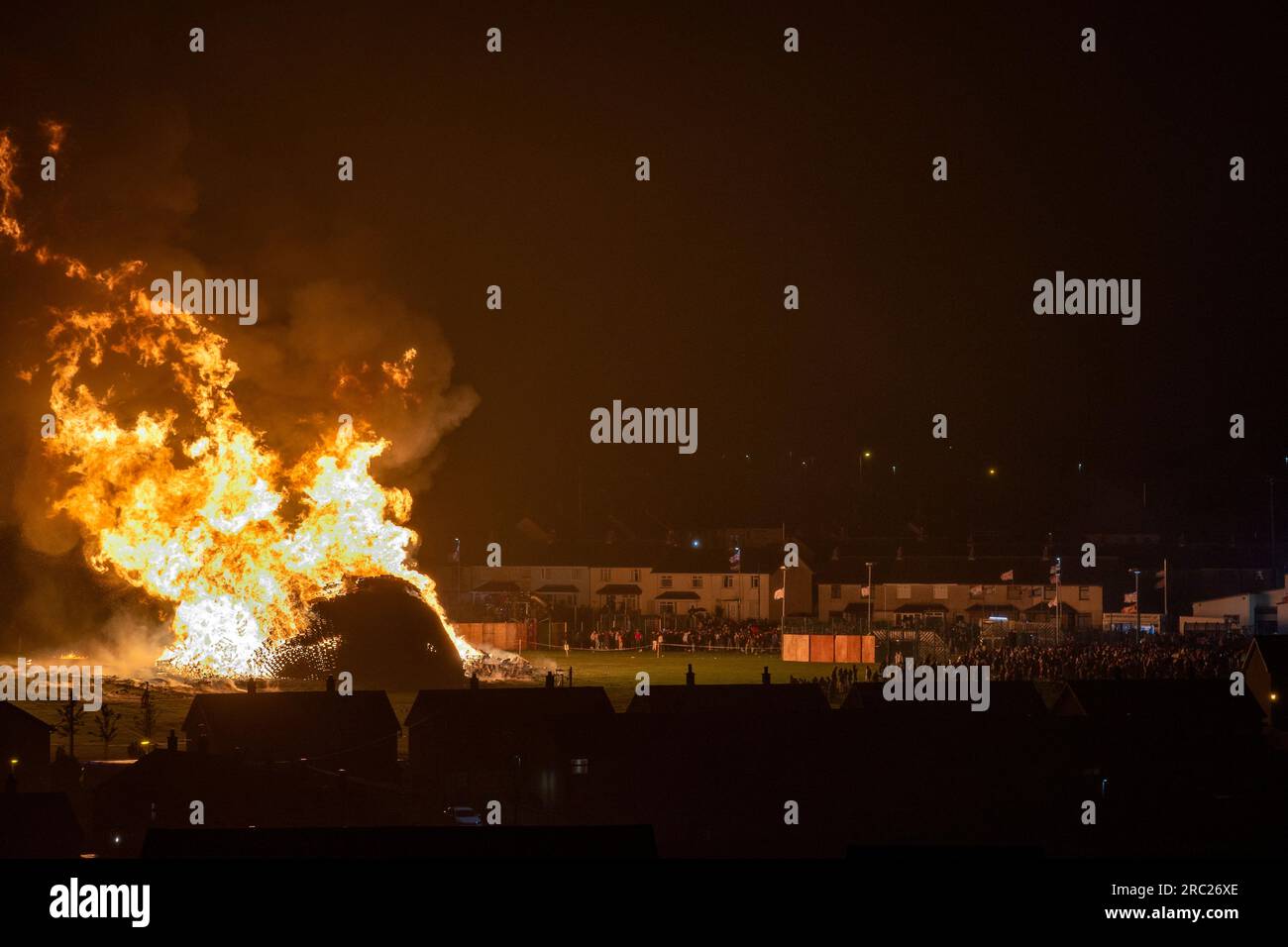 Les gens regardent l'incendie du feu de joie loyaliste de Craigyhill à Larne, Co Antrim, la onzième nuit. Inaugurant les douzième commémorations. Date de la photo : mercredi 12 juillet 2023. Banque D'Images